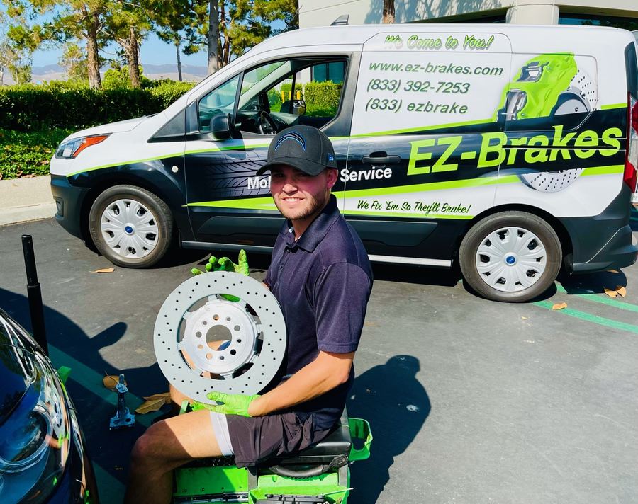 EZ-Brakes technician holding a brake rotor beside the service van