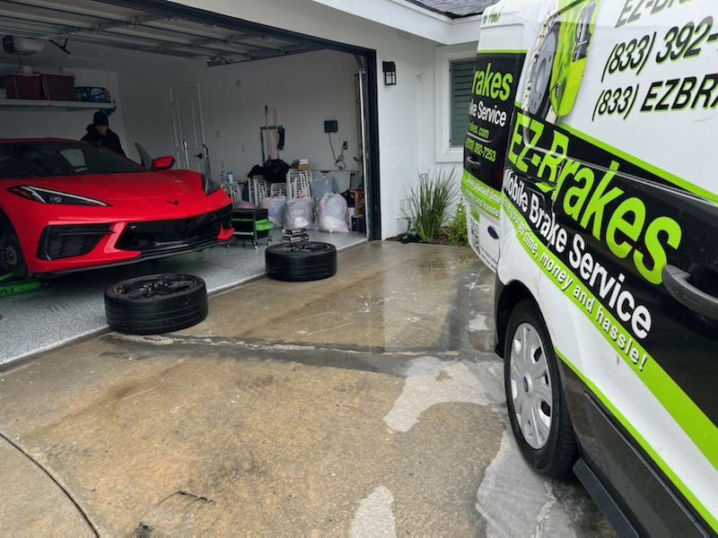 EZ-Brakes van parked in a driveway next to a Corvette C8 in the garage