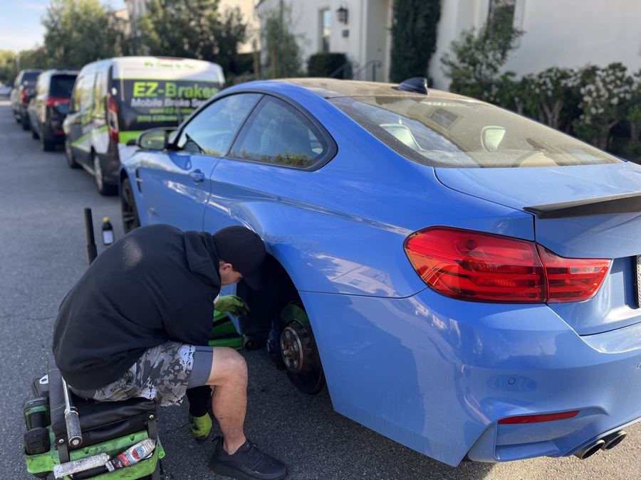EZ-Brakes van parked next to a blue BMW M4 during a mobile brake service