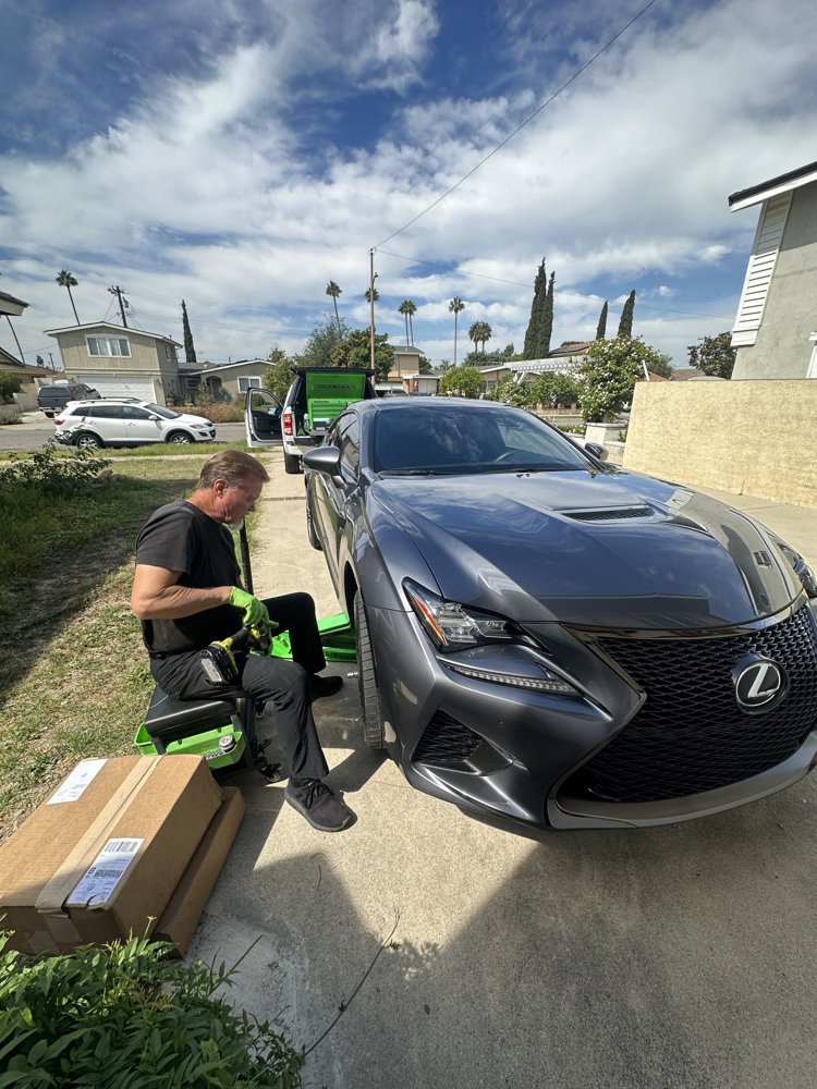 Gray Lexus RC F raised on a jack during mobile brake service in a Huntington Beach driveway