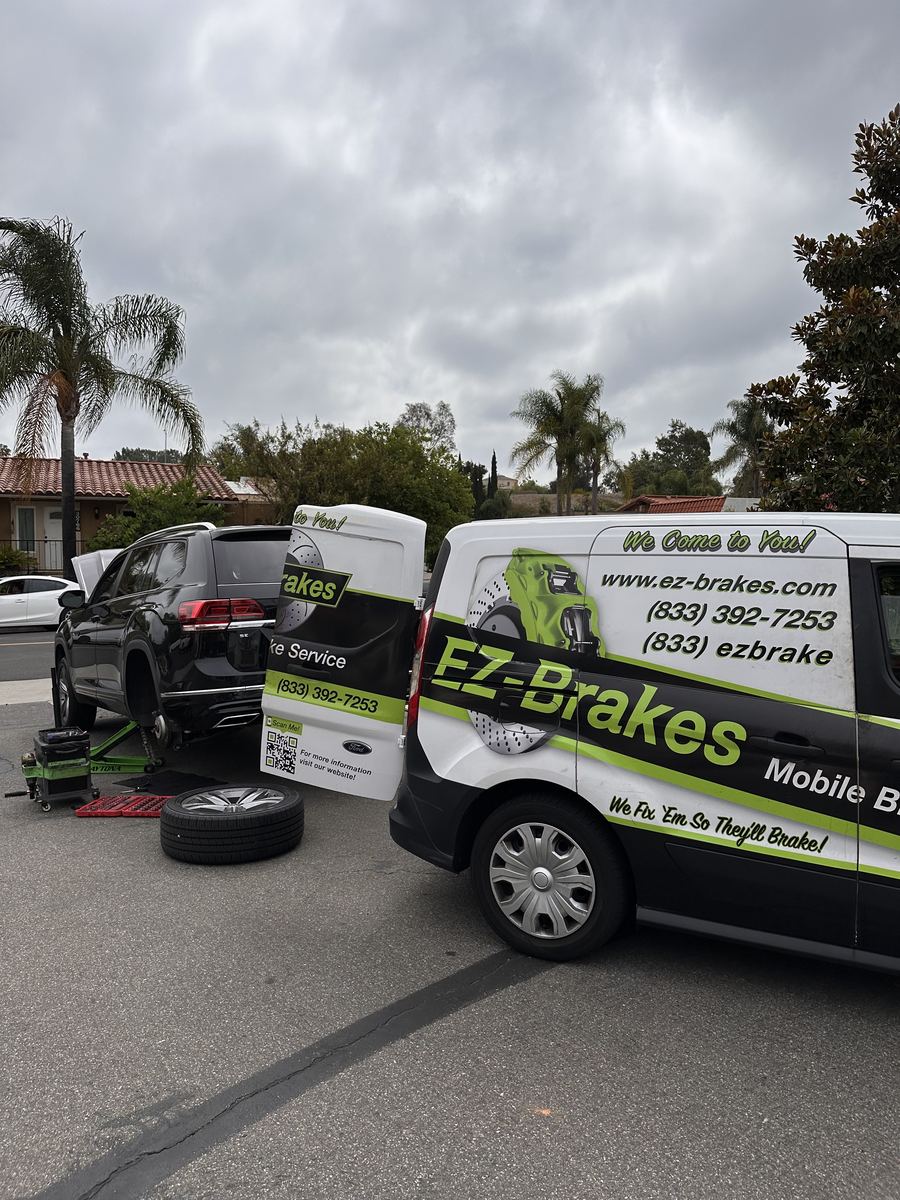 Matte black Nissan 370Z being serviced with the EZ-Brakes van parked nearby