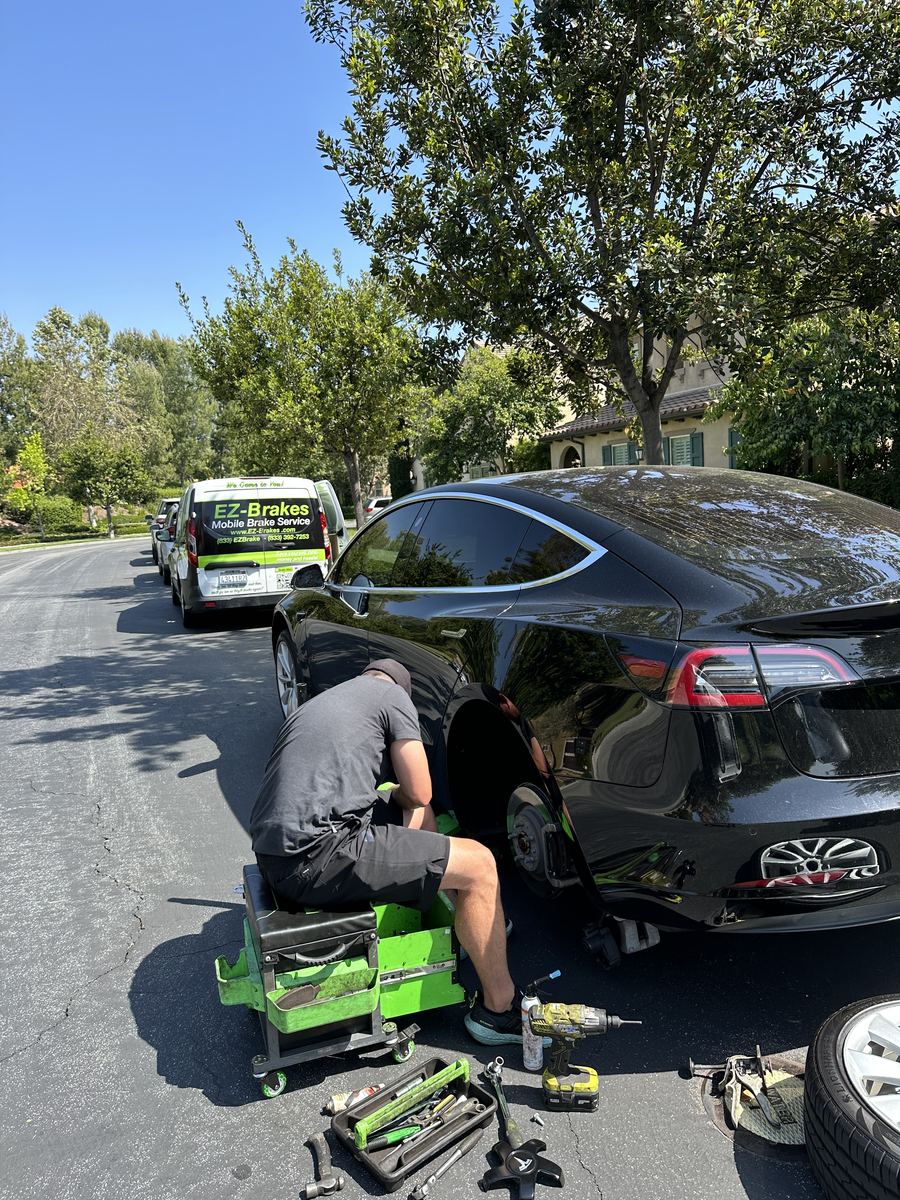 Mobile brake technician servicing a black Tesla Model S rear wheel