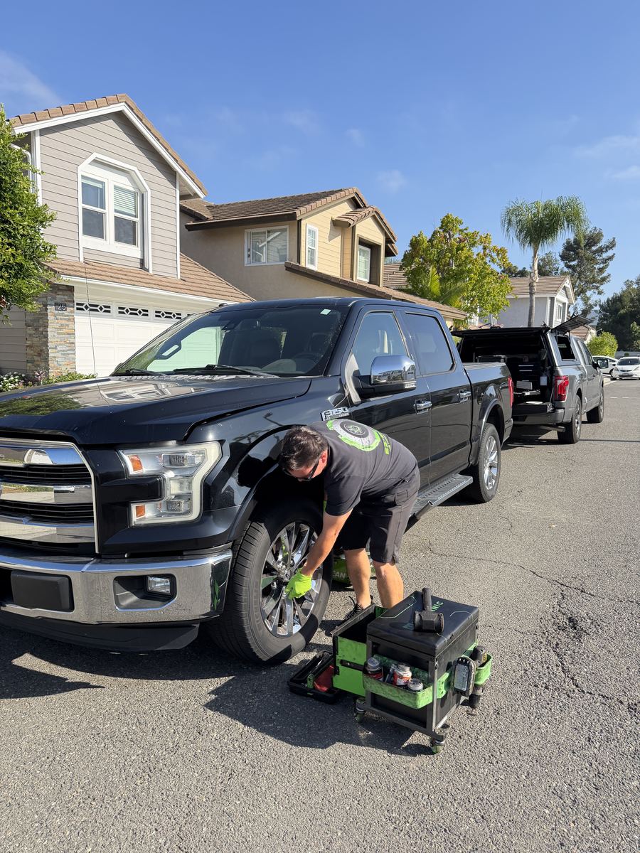 Mobile brake technician servicing a Ford F-150 truck in a driveway
