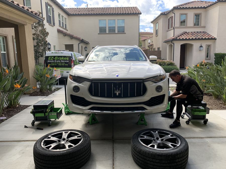 Mobile brake technician servicing a Maserati Levante in a driveway