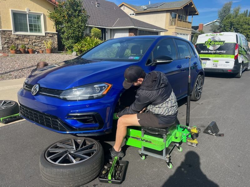 Mobile brake technician servicing a VW Golf R in a driveway