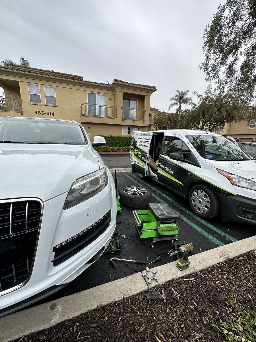 Mobile brake technician servicing a white Audi Q7 next to the EZ-Brakes van