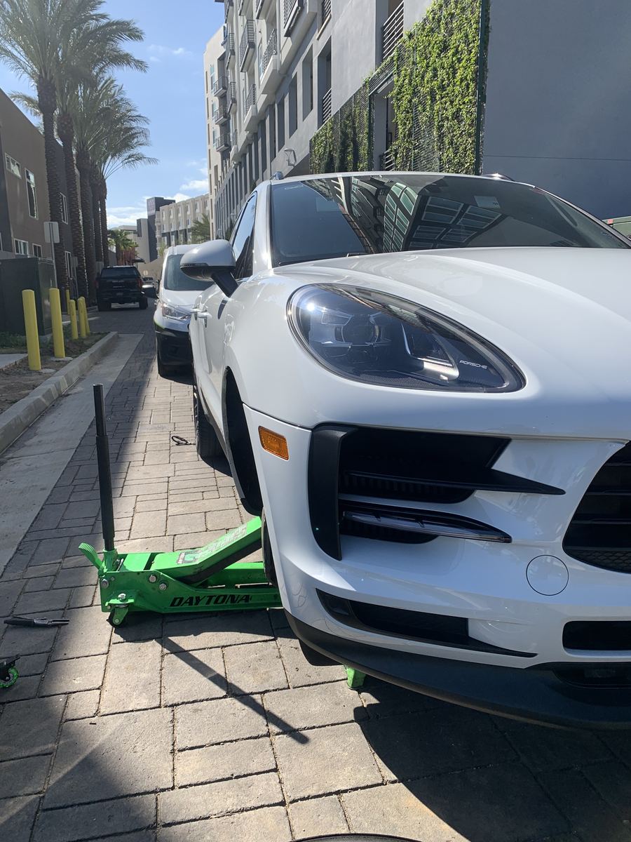 Porsche Macan raised for mobile brake service on a city sidewalk