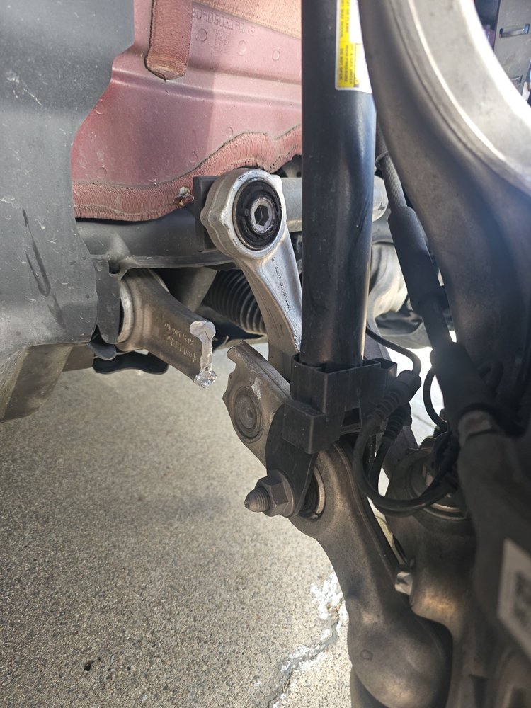 Rear control arm and suspension components exposed during a mobile suspension repair