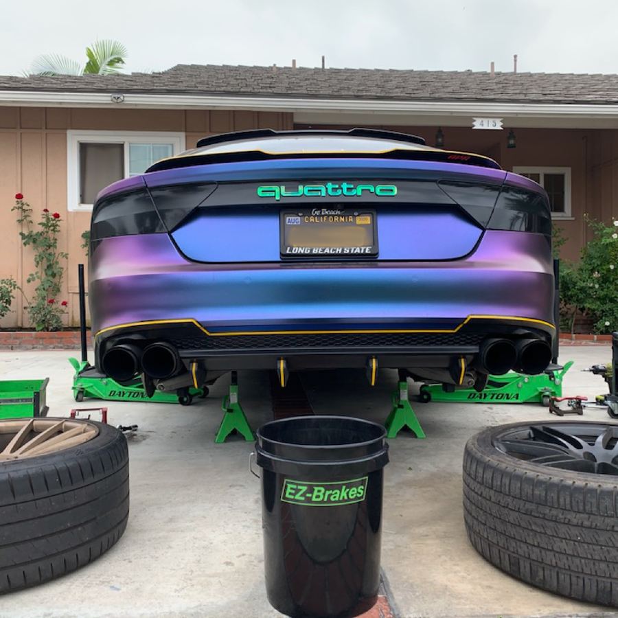 Rear view of a custom-wrapped Audi RS7 on jack stands during mobile service