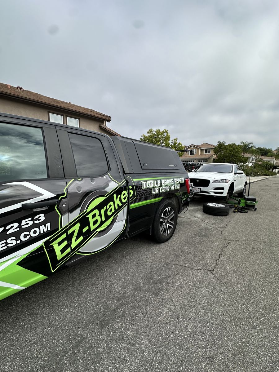 Silver Porsche Cayenne raised for mobile brake service in a driveway