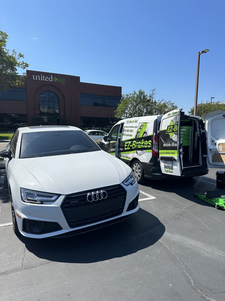 EZ-Brakes van parked beside a white Audi A4 during mobile brake service in a Tustin parking lot