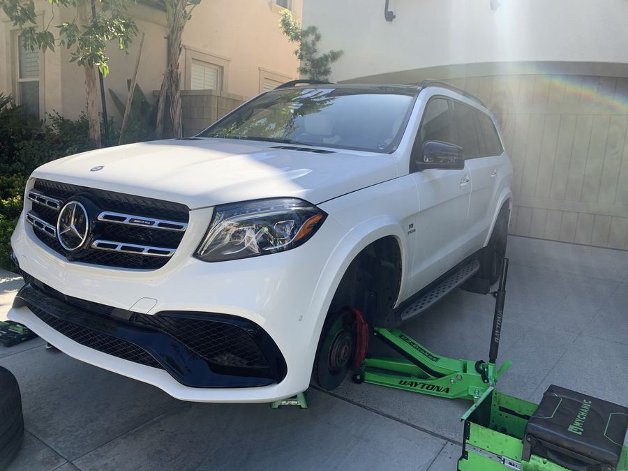 White Mercedes-AMG GLS raised for mobile brake service in a driveway