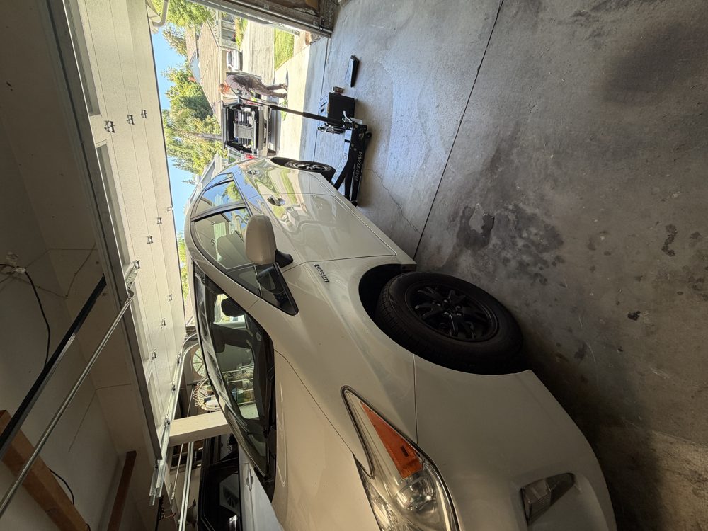 White Toyota Prius up on a jack during mobile brake service in a Laguna Niguel garage